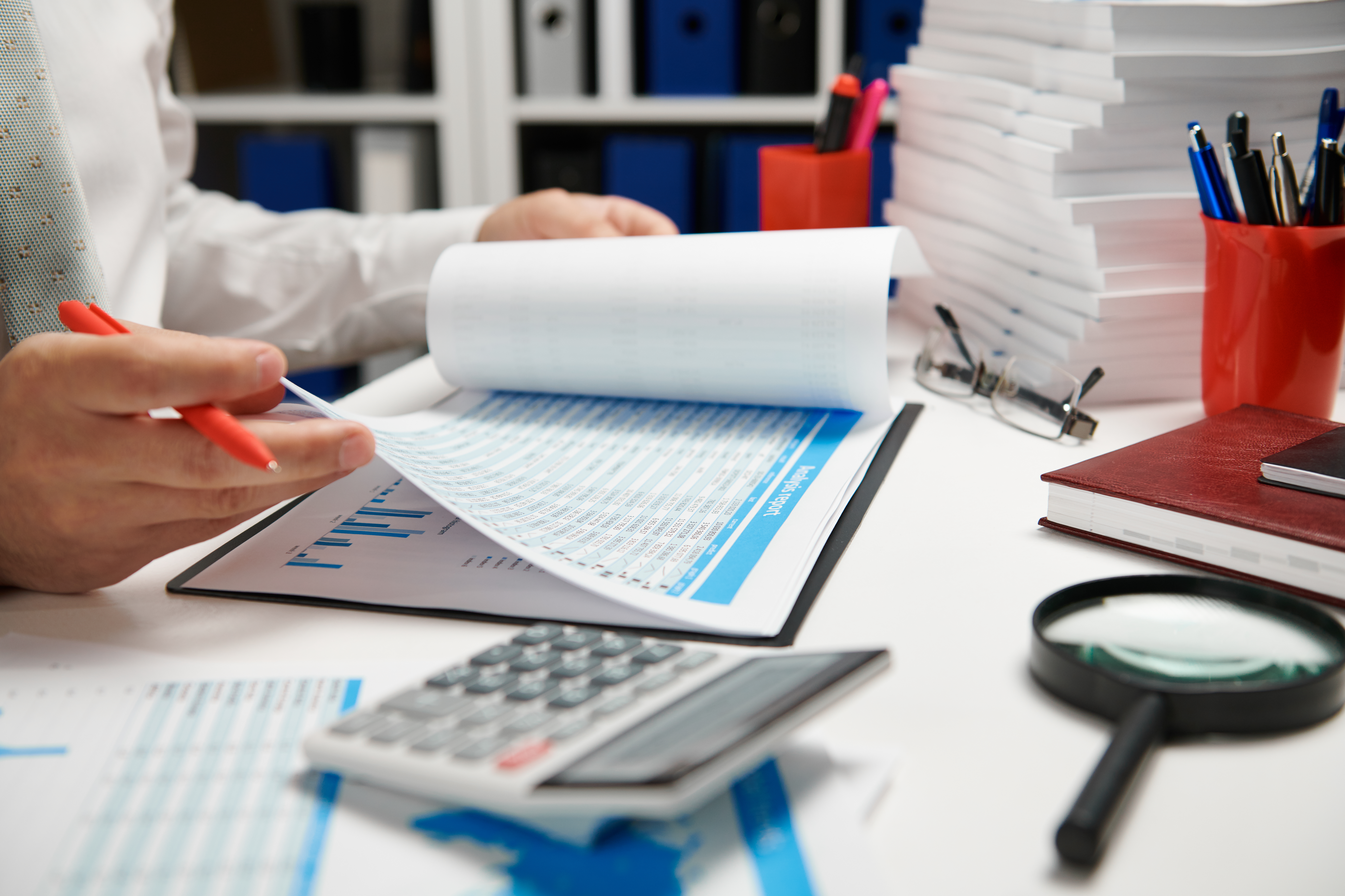 Businessman working and calculating, reads and writes reports. Office employee, table closeup. Business financial accounting concept.