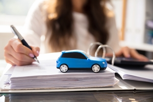 Businesswoman Working On Documents With Small Blue Car
